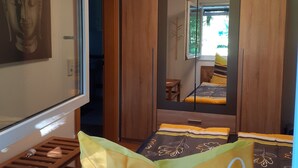 Et soveværelse med seng, garderobe, spejl og loftlampe.