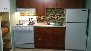 Una cocina compacta con armarios de madera, estufa a gas, fregadero y refrigerador.