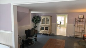 Una sala de estar con televisor, una mesa de madera y un armario.