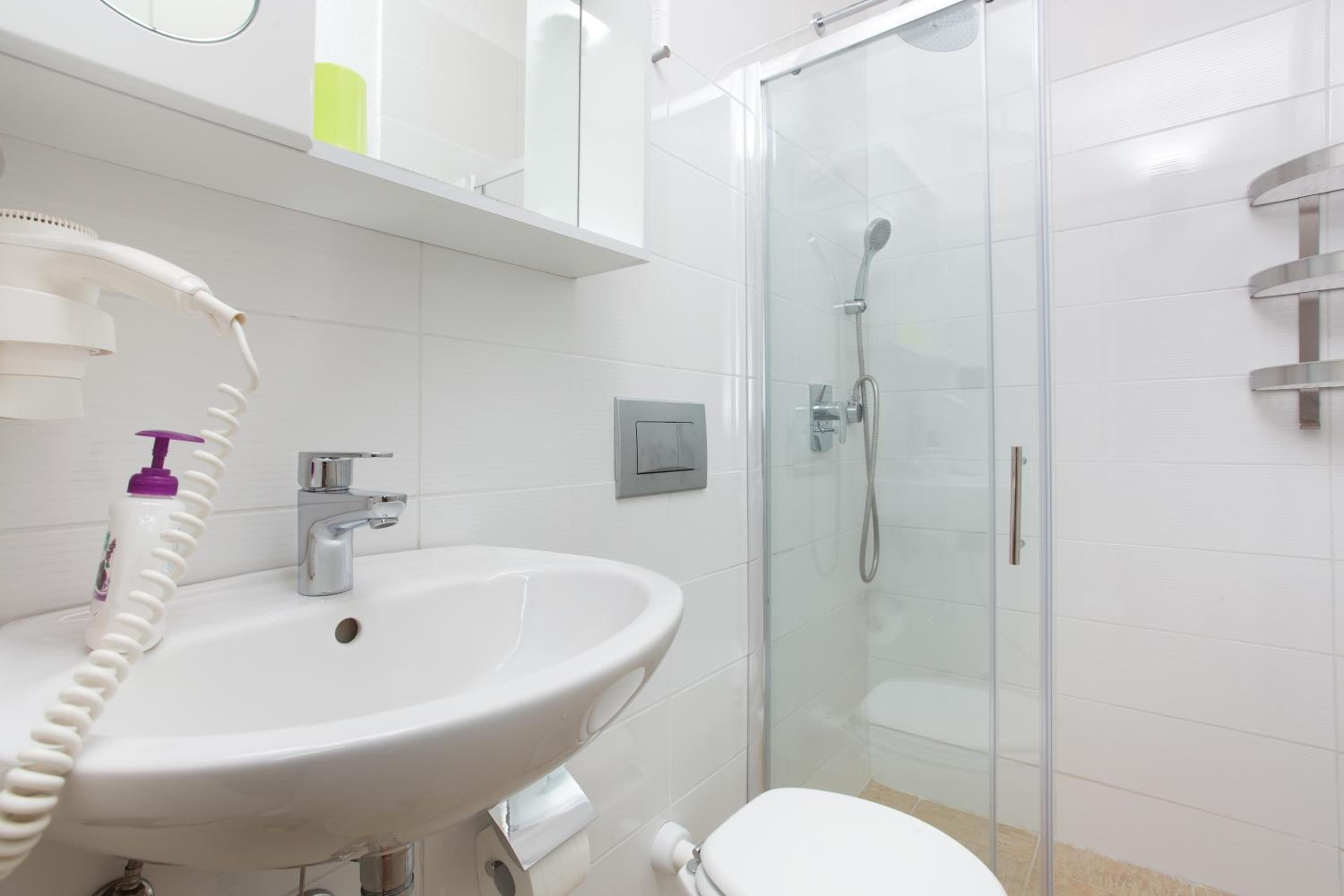 Une salle de bain avec un lavabo blanc, une douche en verre et des toilettes.