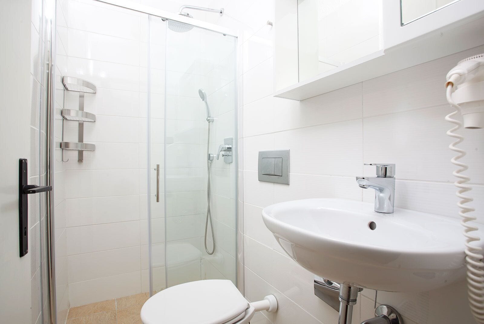 Une salle de bain moderne avec une douche à parois de verre, un lavabo blanc et des toilettes.