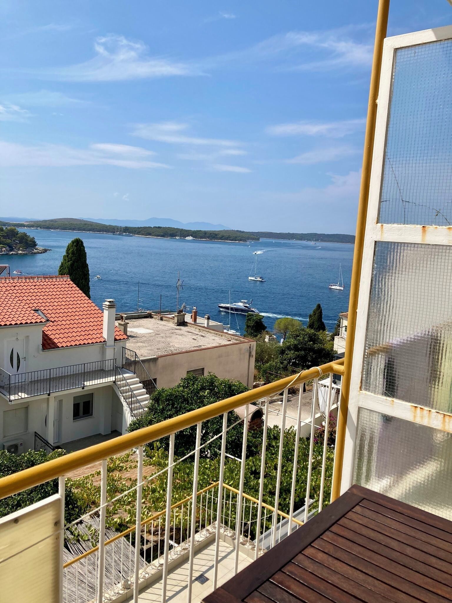 Een balkon met uitzicht op een kustgebied, inclusief gebouwen en boten op het water.