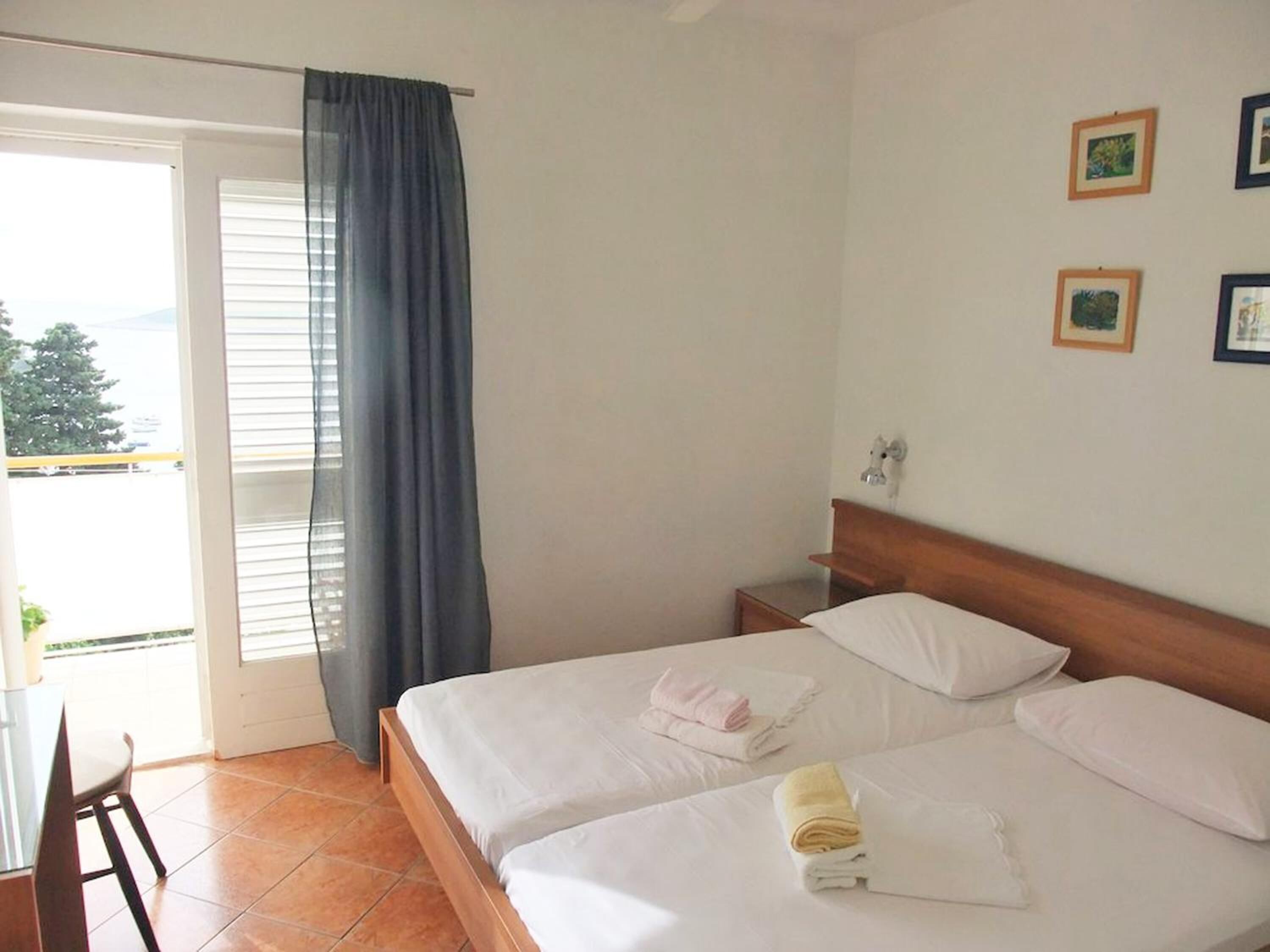 Quarto de hotel com duas camas, varanda e área de refeições.