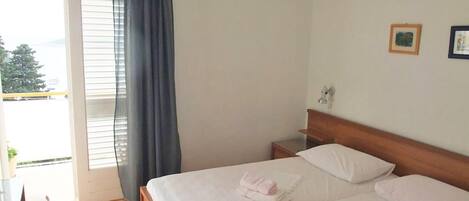 Quarto de hotel com duas camas, varanda e área de refeições.