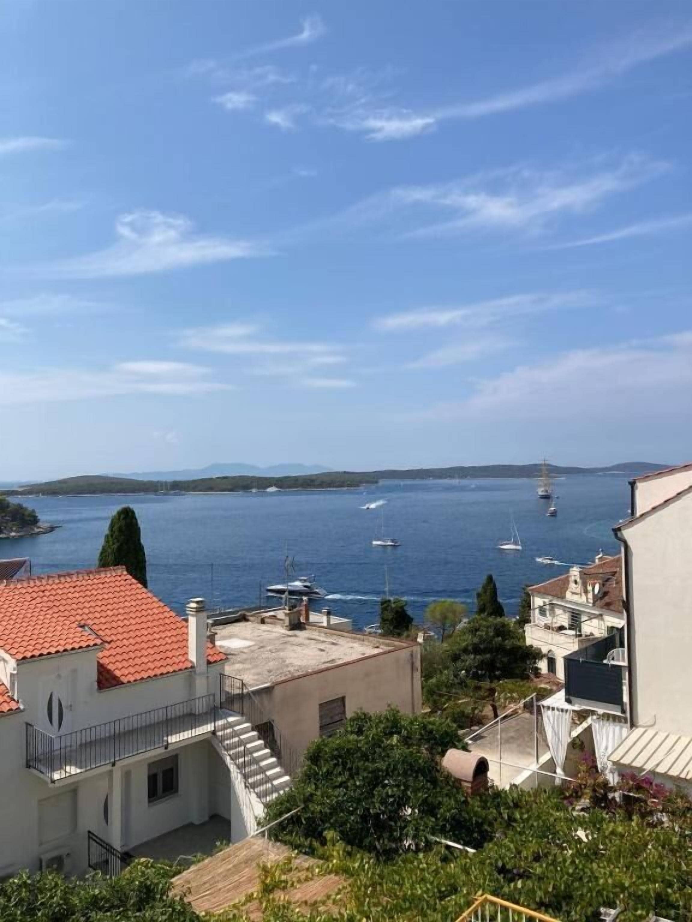 Vista costera con edificios, cielo despejado y barcos en el agua.