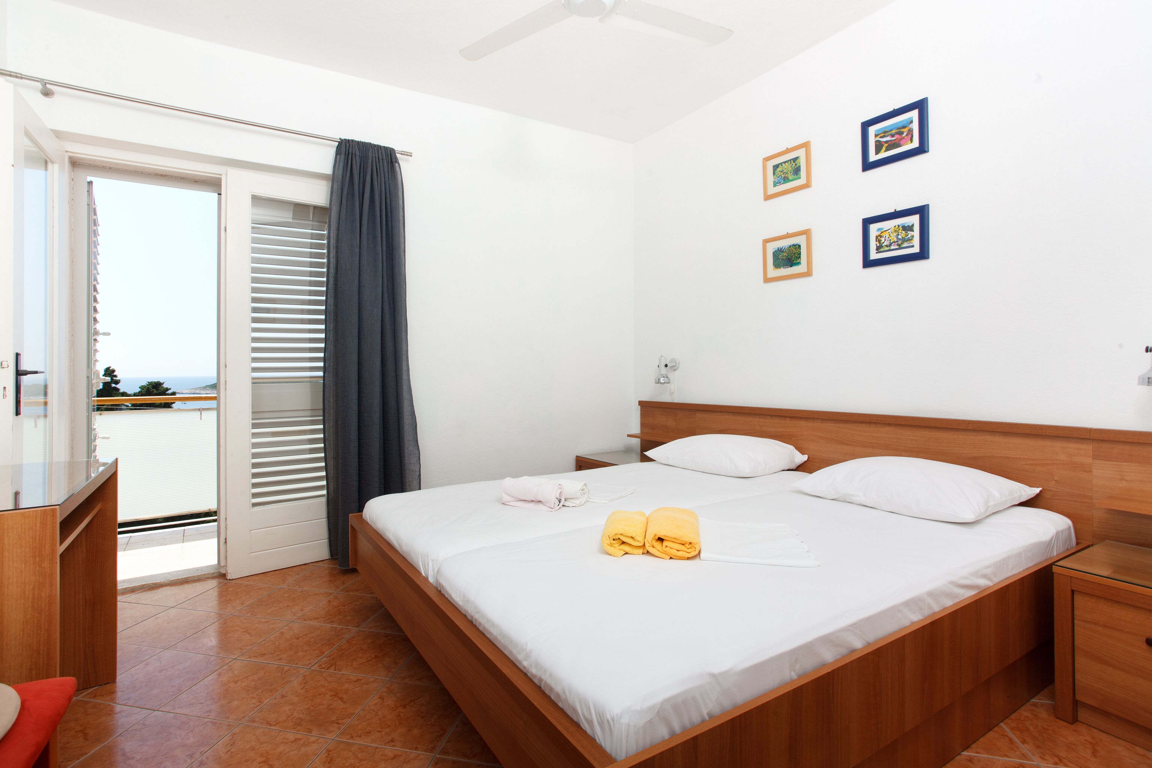 Een slaapkamer met een bed, nachtkastje, bureau en uitzicht door een schuifdeur.