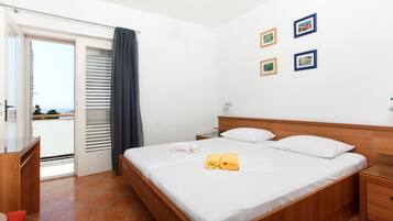 Een slaapkamer met een bed, nachtkastje, bureau en uitzicht door een schuifdeur.