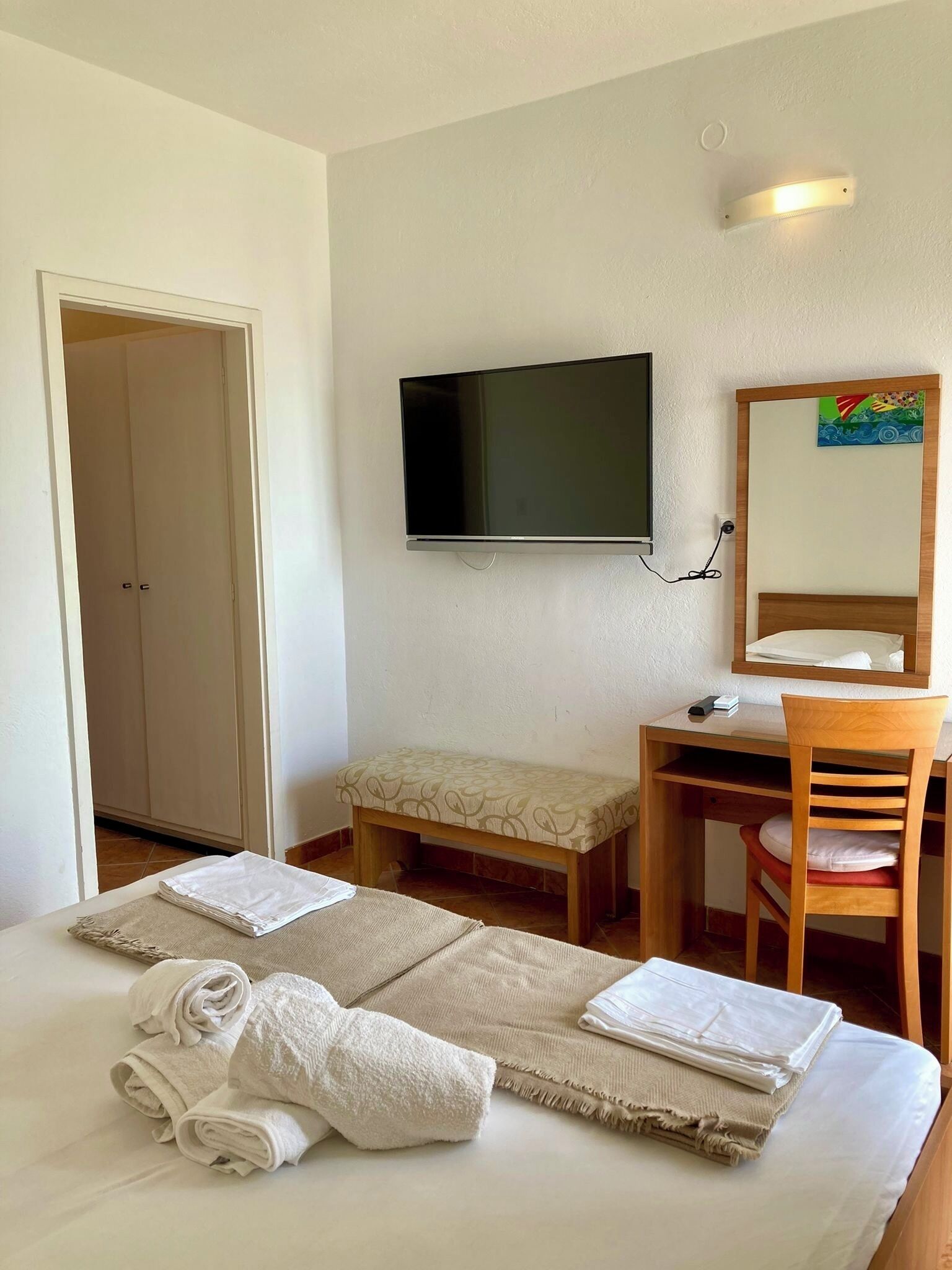 A hotel room with a bed, a desk, a chair, a television, and a bathroom.
