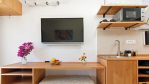 A compact kitchen with a built-in microwave, a small sink, and a flat-screen TV mounted on the wall. - Rooms Vinka Tudor (Hvar)