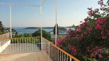 Un balcon avec vue sur la mer et une île lointaine.