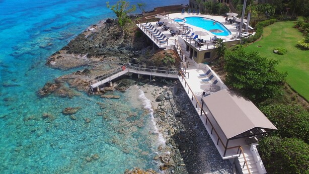 A resort with a pool, a bridge, and a view of the ocean.