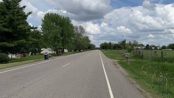 A road with a white dividing line, surrounded by trees and grassy areas.