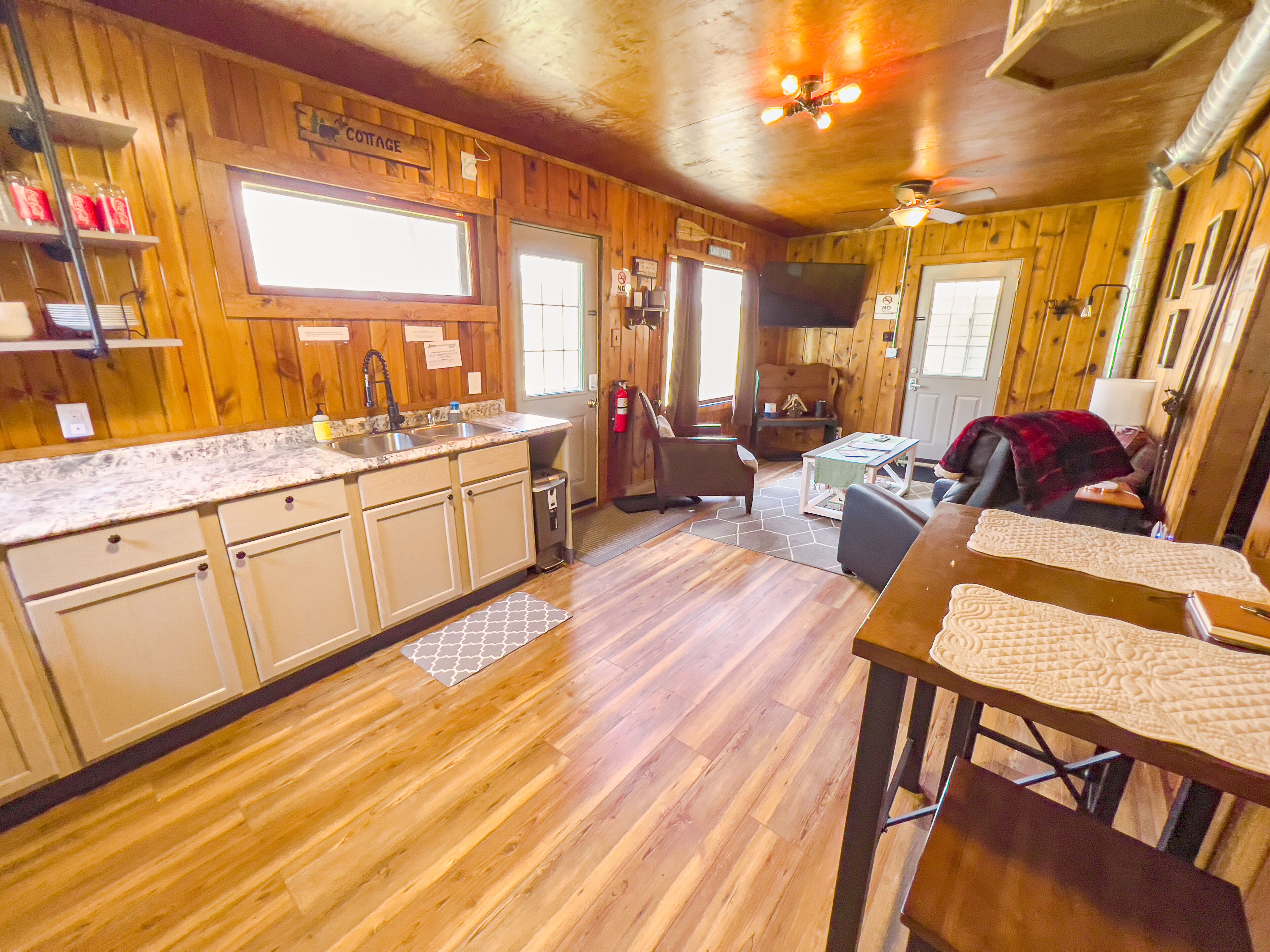 A wooden cabin interior with a kitchen, dining area, and living room.