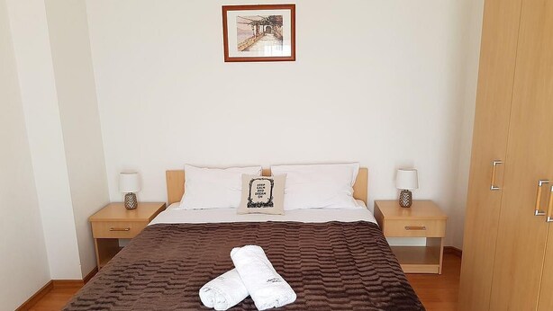 A bedroom with a bed, two nightstands, a wardrobe, and a framed picture on the wall. - Cozy Apartment Neda (Pakostane)
