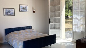 Une chambre à coucher avec un lit, un plafond en bois, une porte donnant sur l’extérieur et deux tableaux encadrés accrochés au mur.