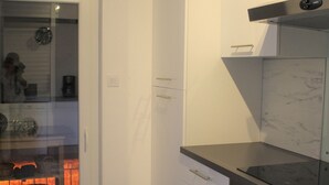 A modern kitchen with white cabinetry, a black countertop, and a built-in oven.