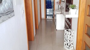 A hallway with wooden doors, a white wall with a cross, a white sink, and a plant. - Spacious Apartment Neda (Pakostane)