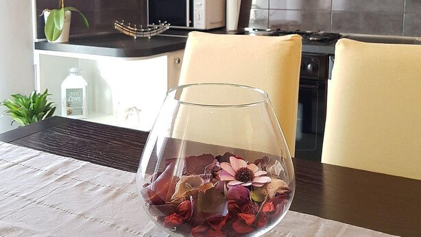 A dining table with a clear glass vase containing dried flowers. - Spacious Apartment Neda (Pakostane)