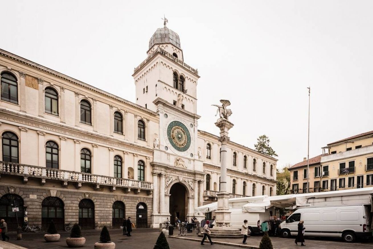 A historic building with a prominent clock tower and a central fountain.
