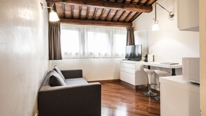 Un salon moderne avec un plafond en bois, un canapé, un téléviseur, un bureau et une chaise.
