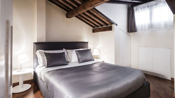 Une chambre à coucher avec un lit, des tables de chevet et un plafond en pente.