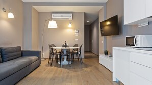 Uma sala de estar moderna com sofá, mesa de jantar, cadeiras, televisão e micro-ondas.