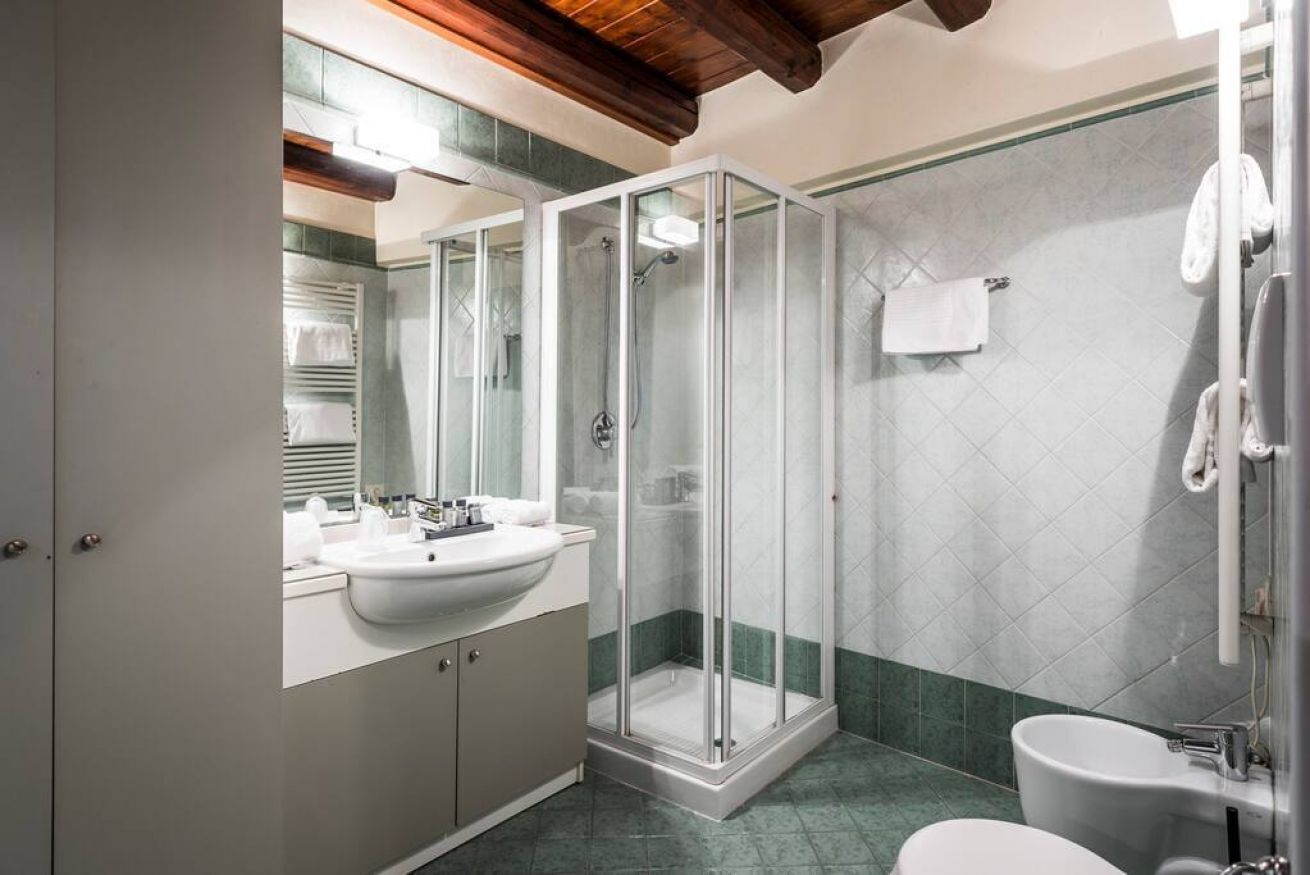 A modern bathroom with a glass-enclosed shower, a sink with a mirror, and a toilet.