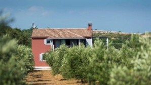 A red building with a tiled roof, surrounded by olive trees. - Villa Pomer (Medulin)