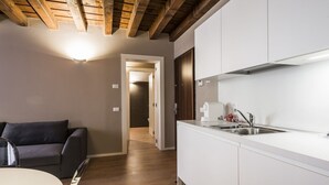 Eine moderne Küche mit weißen Schränken, einer Edelstahl-Spüle und einer Holzbalkendecke.