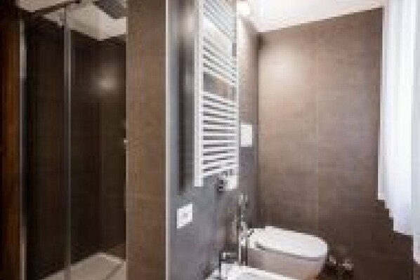 Ein modernes Badezimmer mit Duschkabine, Toilette und Handtuchhalter.