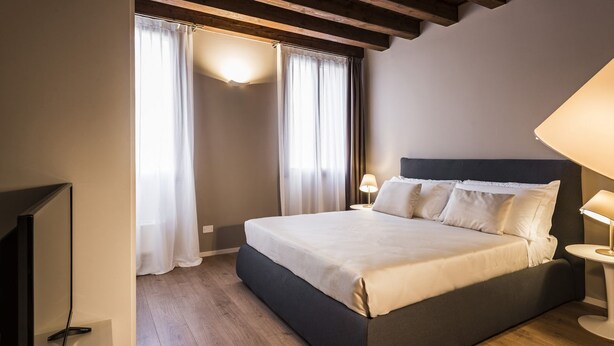 Ein Schlafzimmer mit einem Bett, Vorhängen, einer Lampe und einem Fernseher.