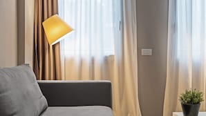 A modern living room with a grey sofa, a floor lamp, and a potted plant. - MyPlace Piazza Vittoria Apartment (Treviso)