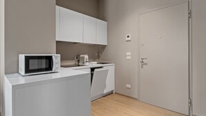 A compact kitchen with a microwave, sink, and white cabinets. - MyPlace Piazza Vittoria Apartment (Treviso)