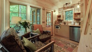 Interior acolhedor de uma cabana, com decoração em madeira, área de jantar e cozinha.