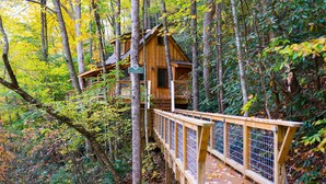 Uma casa na árvore de madeira com um deck de madeira e uma placa com a inscrição 'CEDAR'.