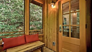 Uma cabana de madeira com um banco e uma porta com fechadura eletrônica.