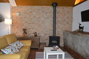 Una sala de estar acogedora con pared de piedra, un sofá, una mesita y una chimenea.