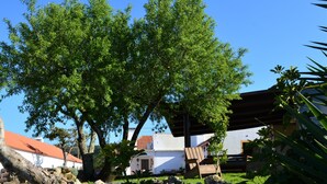 Ein Gebäude mit rotem Dach und weißen Wänden, umgeben von üppigen grünen Bäumen und einer Steinmauer.