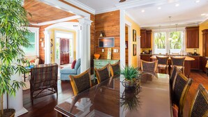 A spacious living room with a dining area, wooden accents, and a large window. - SUNCATCHER~4 Bedroom, 4 Bathroom in Old Town with Pool! (Key West)