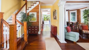 A spacious living area with a wooden staircase, a sofa set, and a dining area. - SUNCATCHER~4 Bedroom, 4 Bathroom in Old Town with Pool! (Key West)