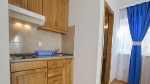 A kitchen with wooden cabinets, a granite countertop, and a blue dish rack. - Apartment Almera N2 (Makarska)