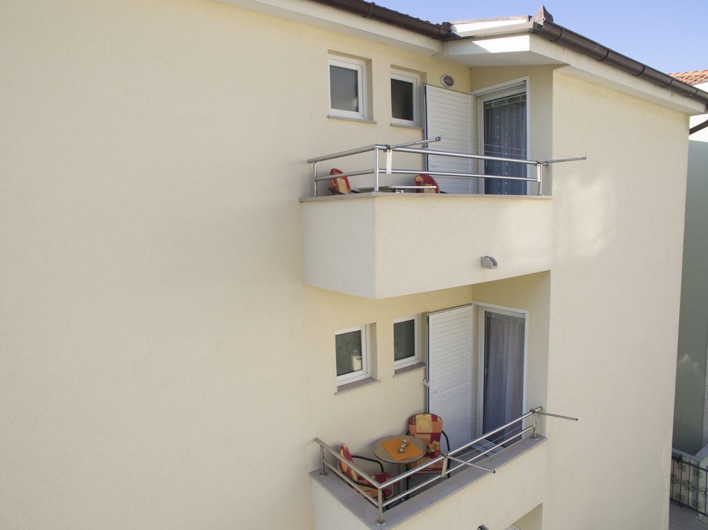A multi-story building with balconies, some with furniture and chairs.