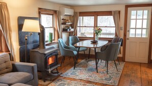 Ein gemütliches Wohnzimmer mit Kamin, bequemen Sitzmöglichkeiten und einem Essbereich mit Tisch und Stühlen.