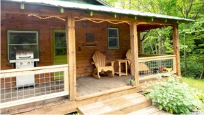 A wooden cabin with a porch, a grill, and Adirondack chairs. - Private Mountain Retreat near Hot Springs & Appalachian Trail (MARSHALL)