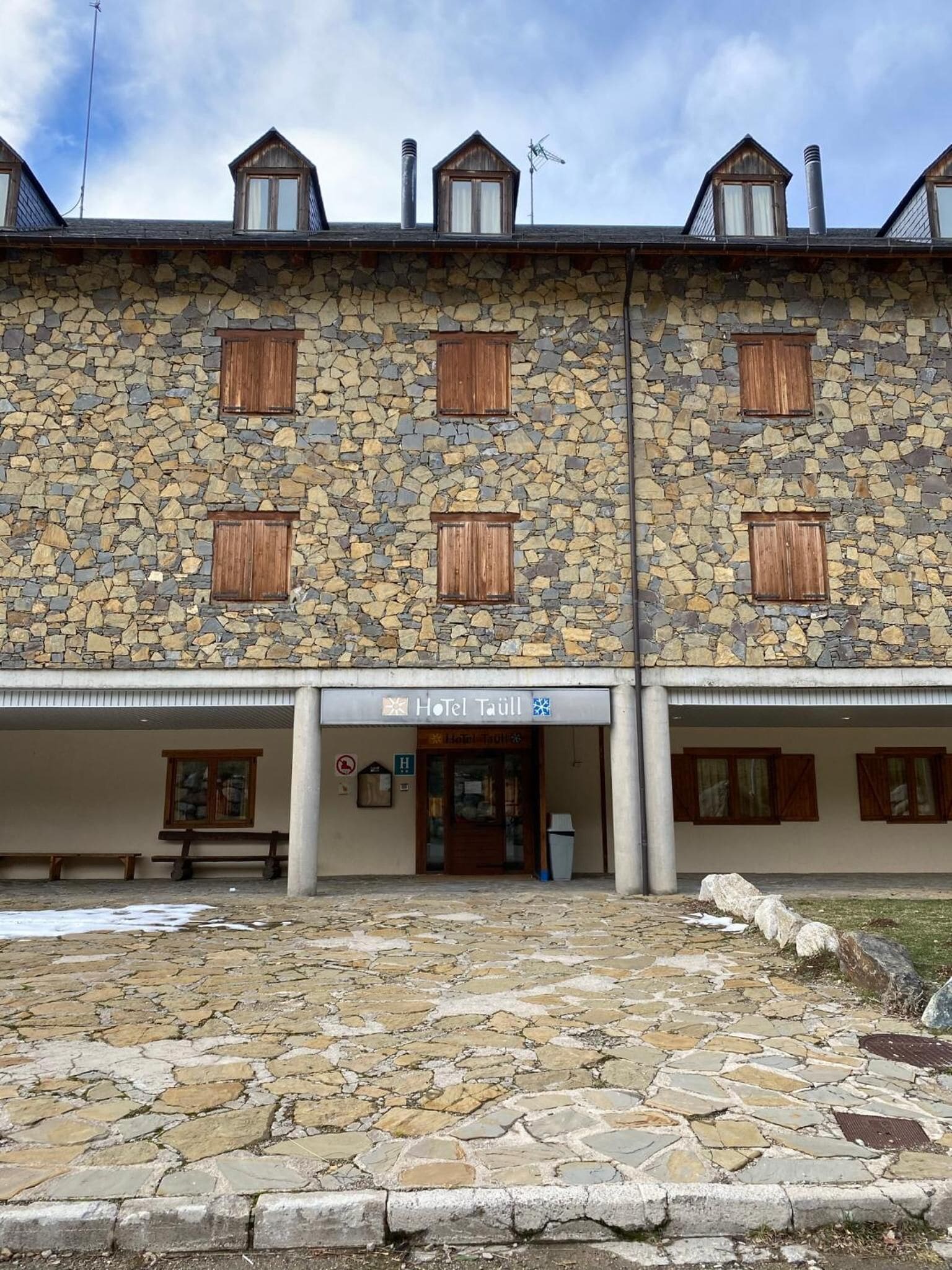 Un edificio de piedra con un cartel que dice "Hotel Taüll".