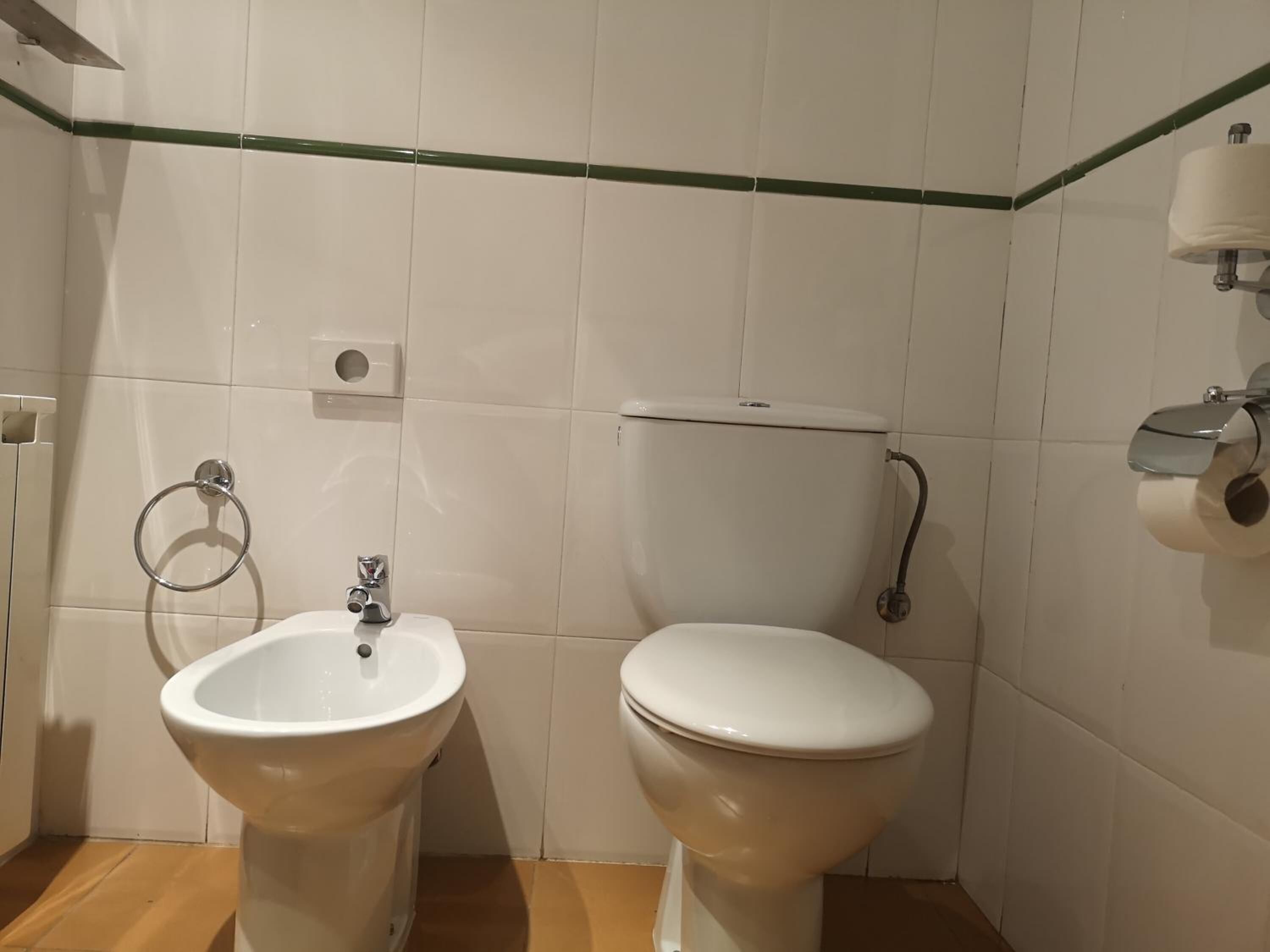 Une salle de bain équipée d’un bidet, de toilettes et d’un porte-serviettes.
