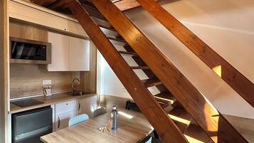 A modern kitchen with a built-in microwave, a sink, and a dining area with a wooden table and chairs.