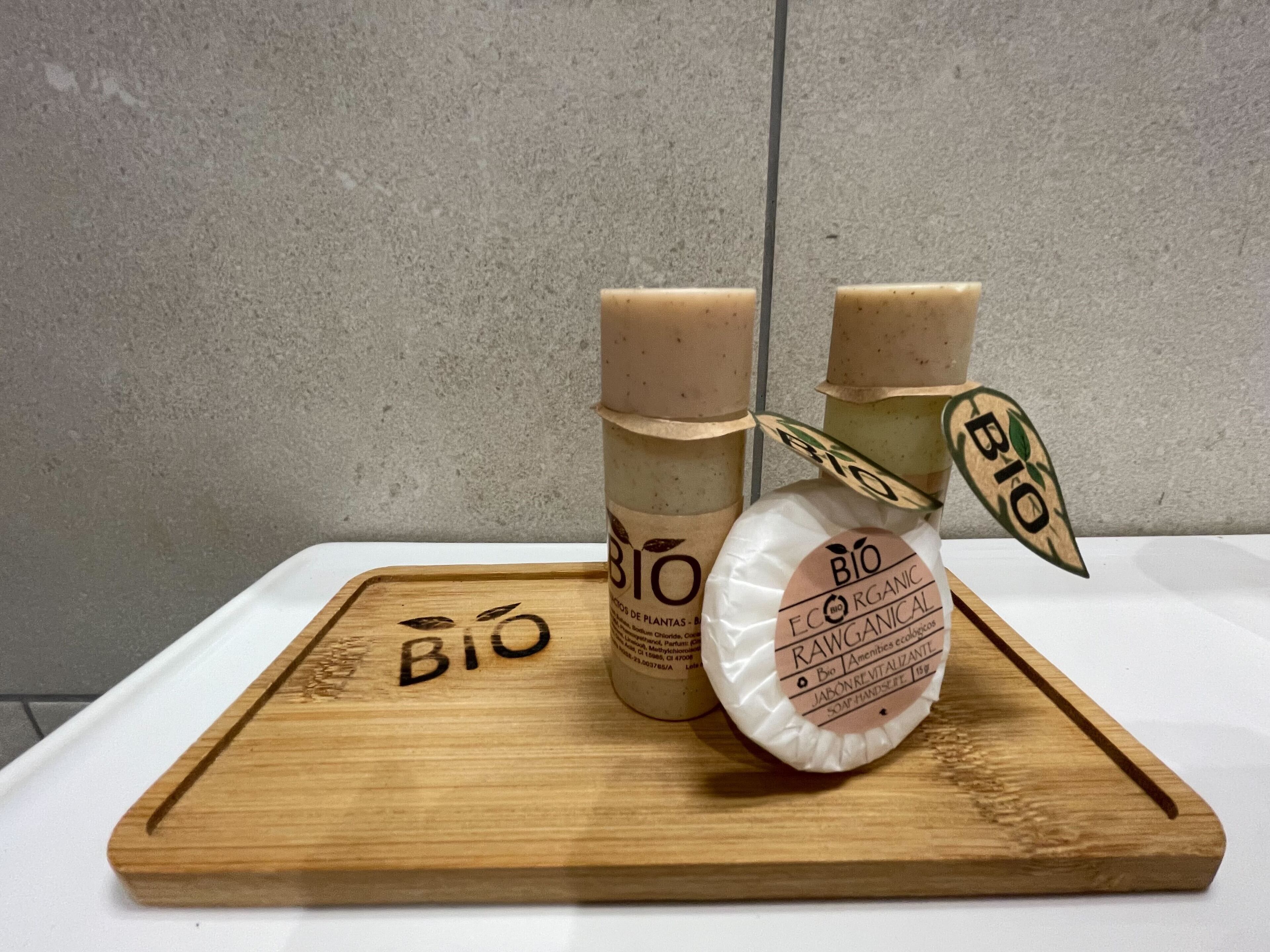 Una bandeja de madera con tres botellas de jabón orgánico y un bloque de madera con la palabra 'BIO'.