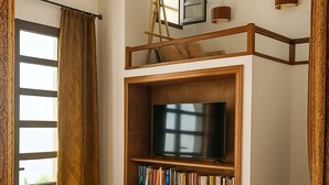 A living room with a TV, bookshelves, a sofa, and a staircase. - Private_vacation_home (El Jadida)