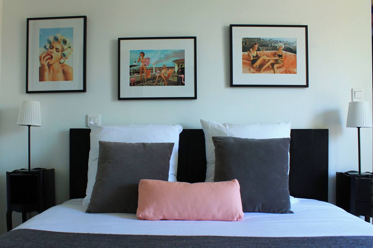 A hotel room with a large bed, two side tables, and three framed pictures on the wall.